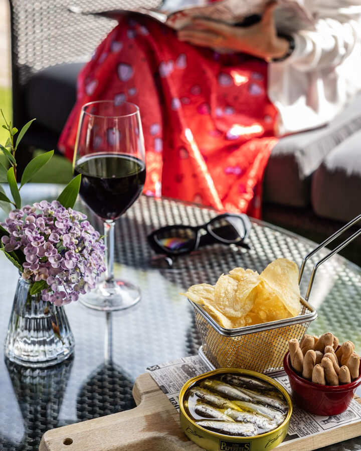 Mesa con aperitivos y chica leyendo revista de fondo