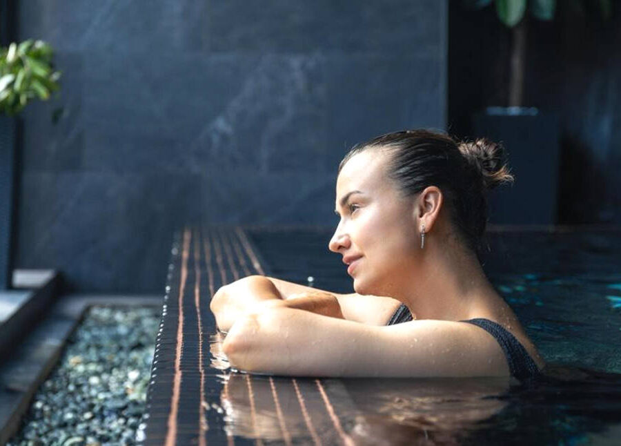 Mujer disfrutando de la piscina de un hotel para escapadas relax.