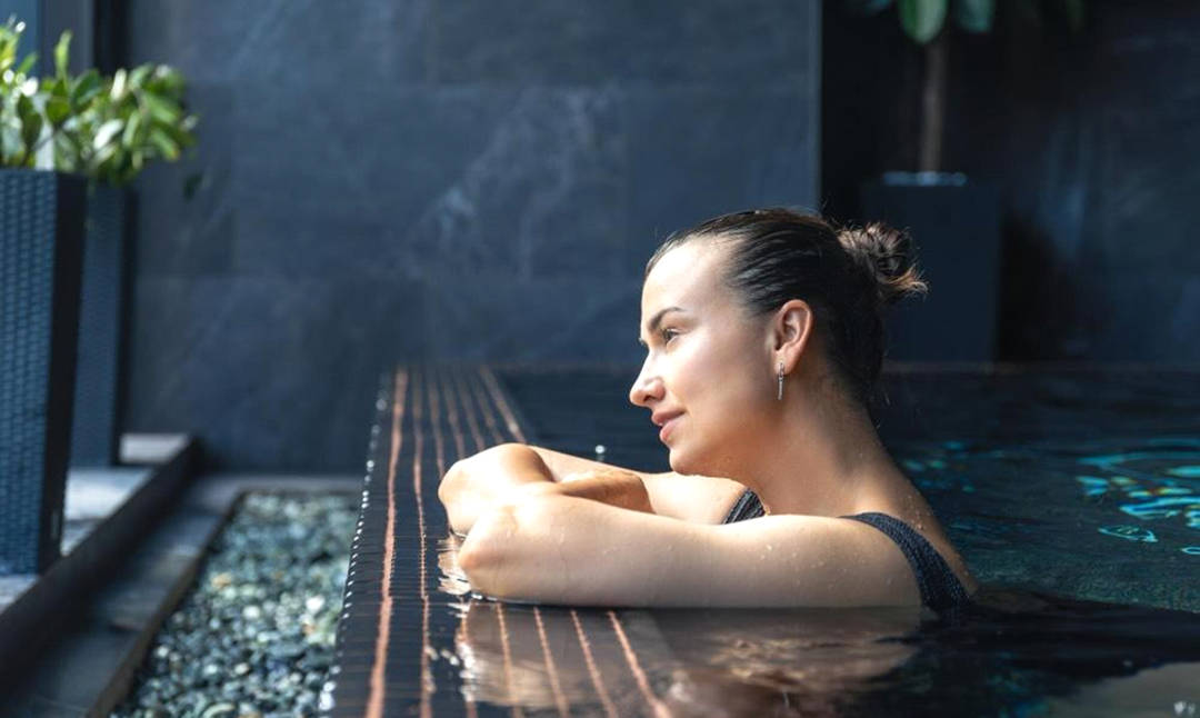 Mujer disfrutando de la piscina de un hotel para escapadas relax.